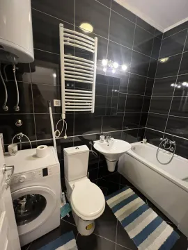 A bathroom with black tiles, a bathtub, and a washing machine. - image 8