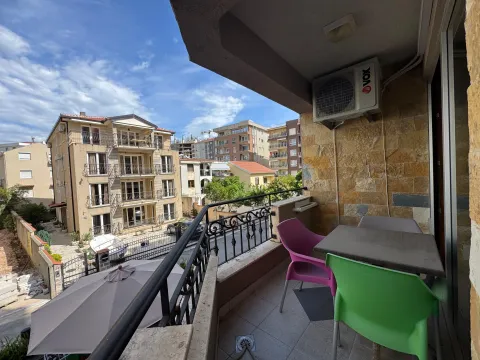 Covered balcony with seating set and view of the street and surrounding buildings. - image 14