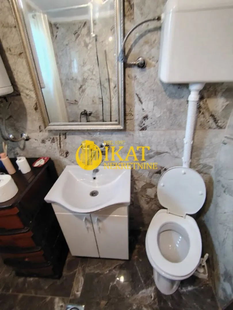 Manje kupatilo sa umivaonikom, WC šoljom i ogledalom.