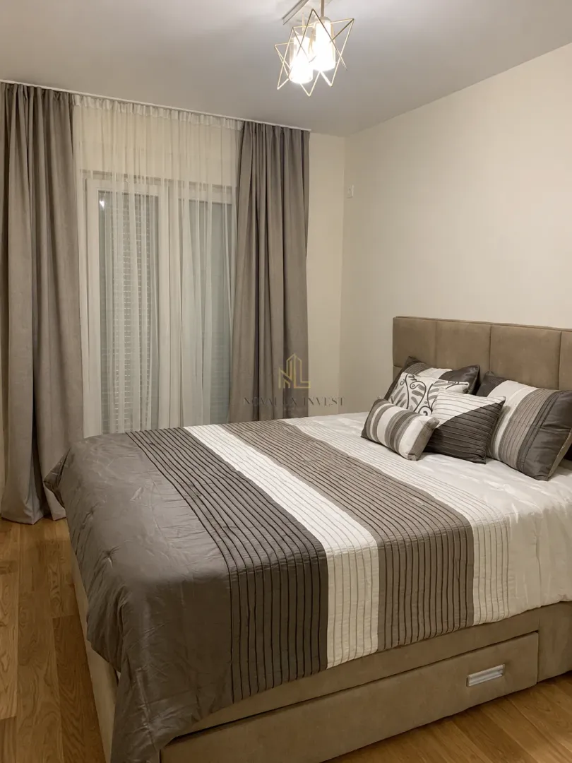 Furnished bedroom with a double bed and a window with curtains.
