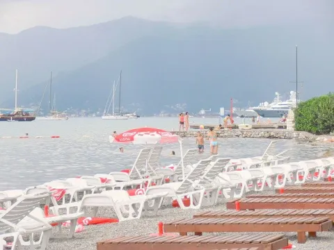 Pogled na plažu sa ležaljkama i more sa brodovima u daljini. - image 9