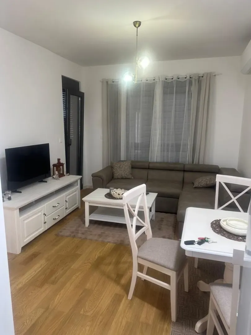 Living room with a sofa, TV unit, and dining table.