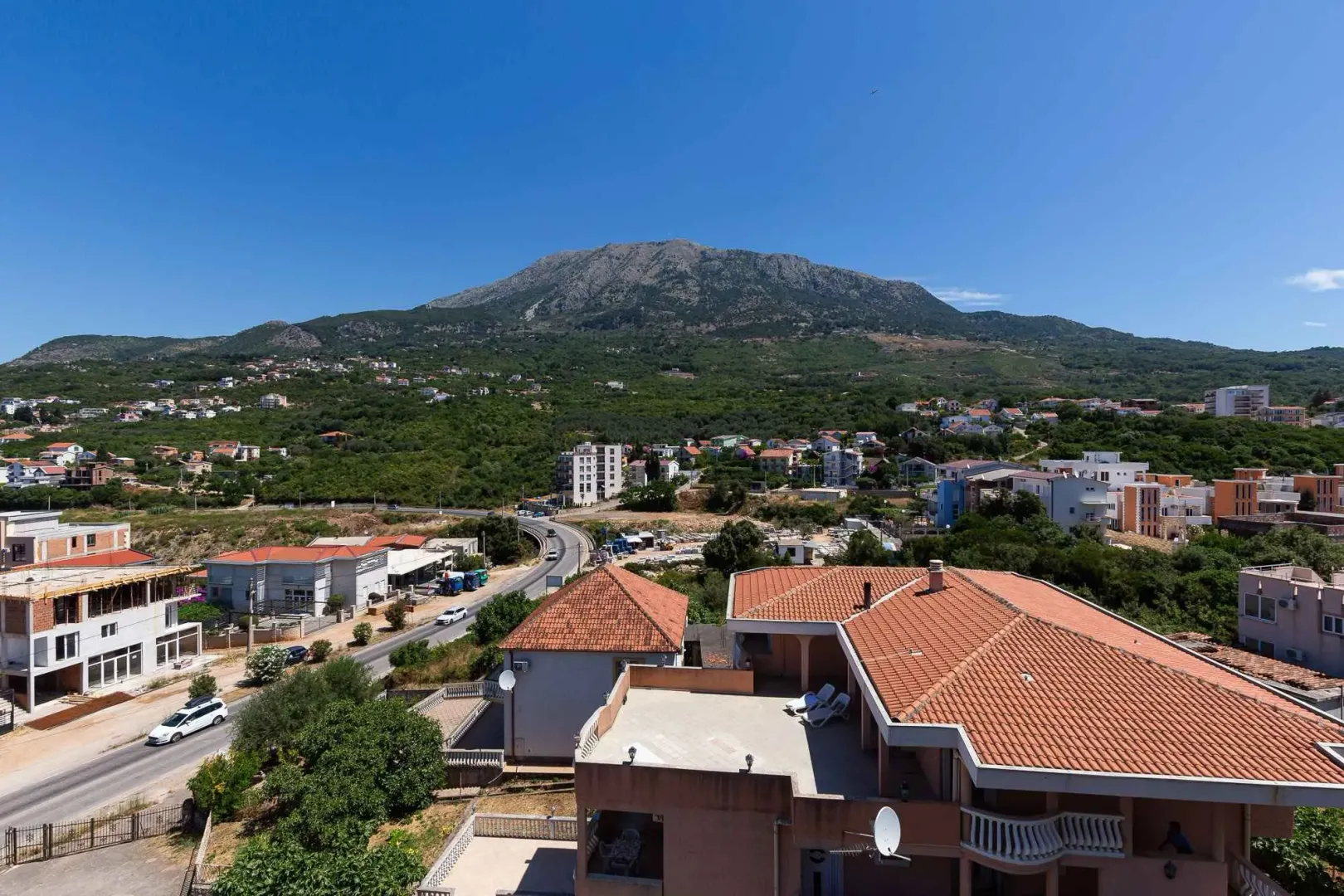 Pogled iz vazduha na okolno naselje i planinu u pozadini.
