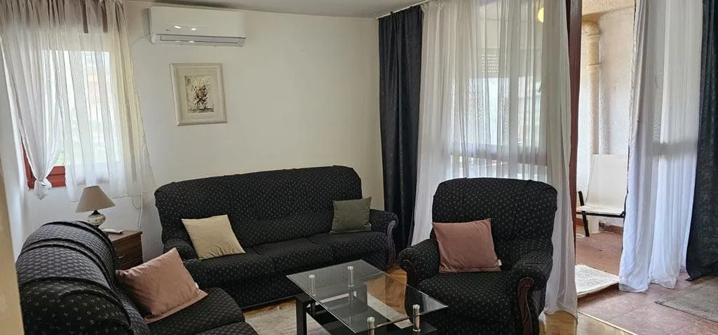 Dnevna soba sa garniturom za sjedenje, stolićem i klima uređajem.