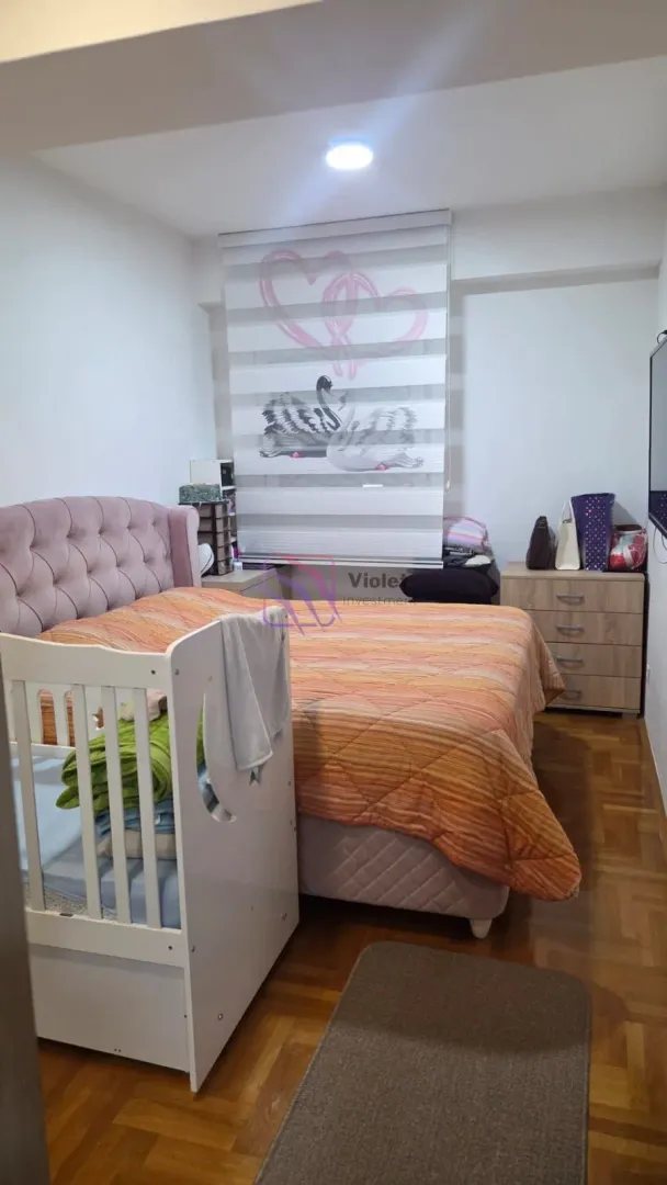 Namještena spavaća soba sa bračnim krevetom i krevetcem za bebe.