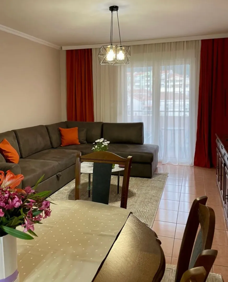 Living room with a sectional sofa, coffee table, and dining table in the foreground.