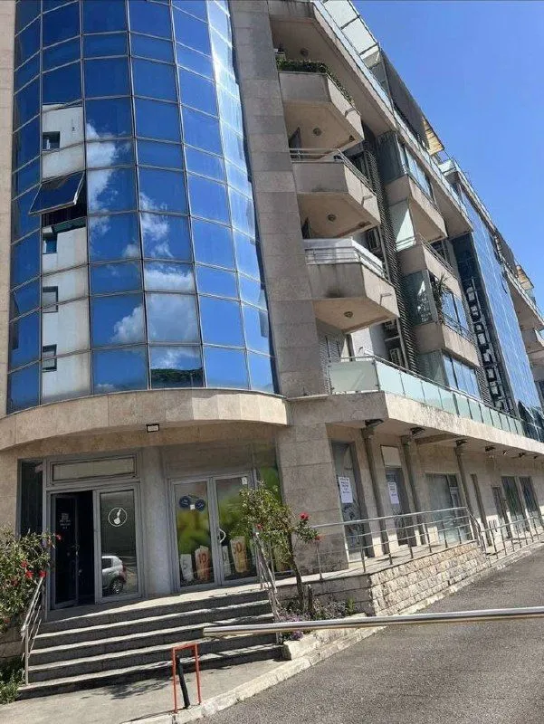 Exterior view of a modern multi-family building with a glass facade and balconies.