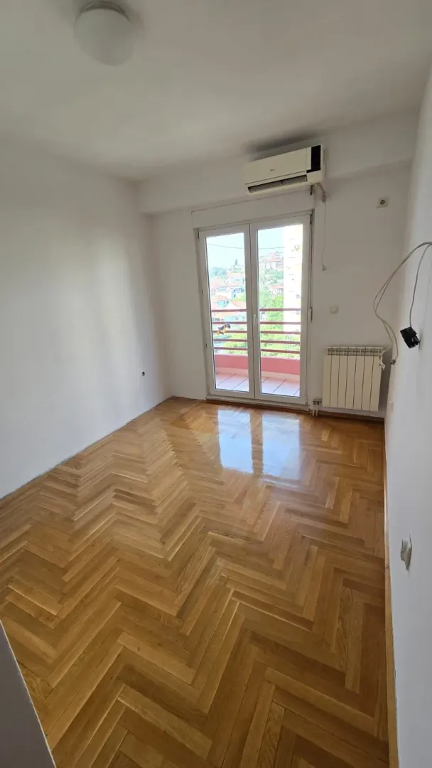 Prazna soba sa parketom i izlazom na terasu.
