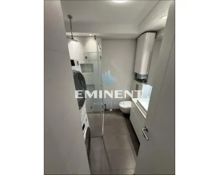 Modern bathroom equipped with a walk-in shower and a washing machine. - image 16