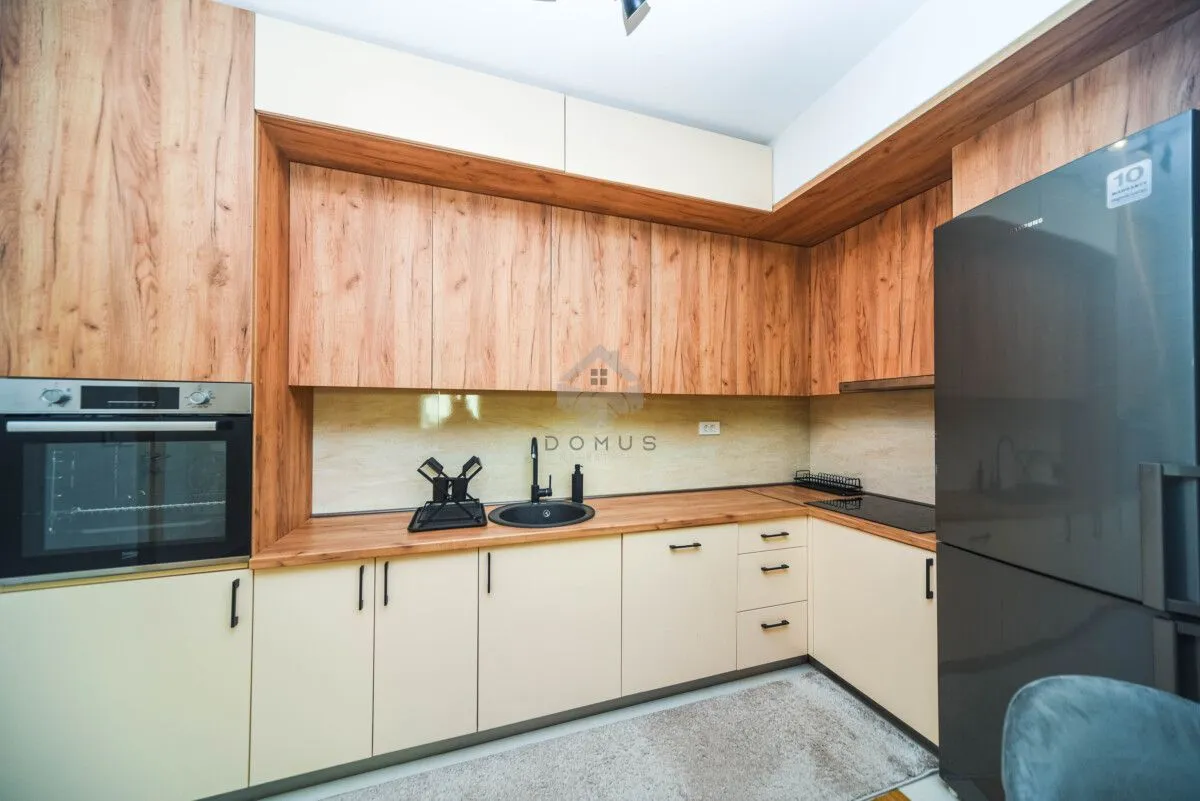 Kitchen with wooden cabinetry, built-in oven and black refrigerator.