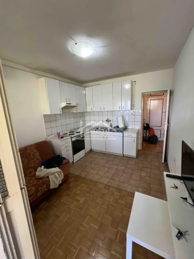 Small kitchen with white units and a seating area with a sofa.