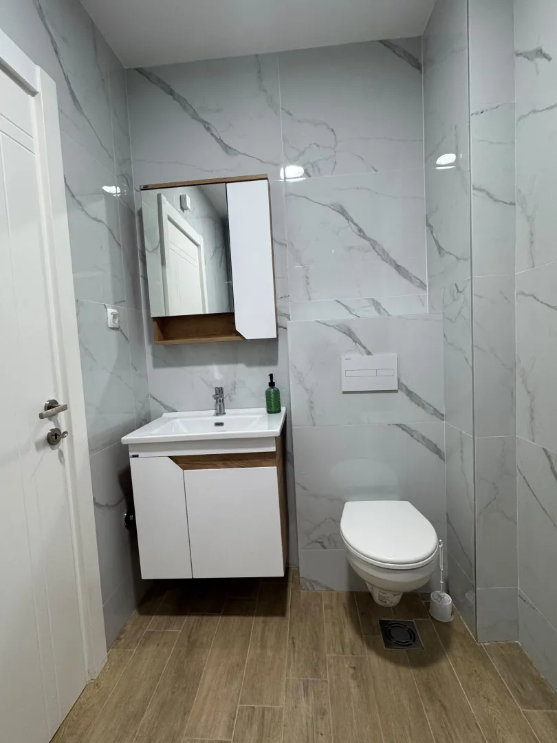 Modernly equipped bathroom with a washbasin and toilet tiled with marble-look tiles.