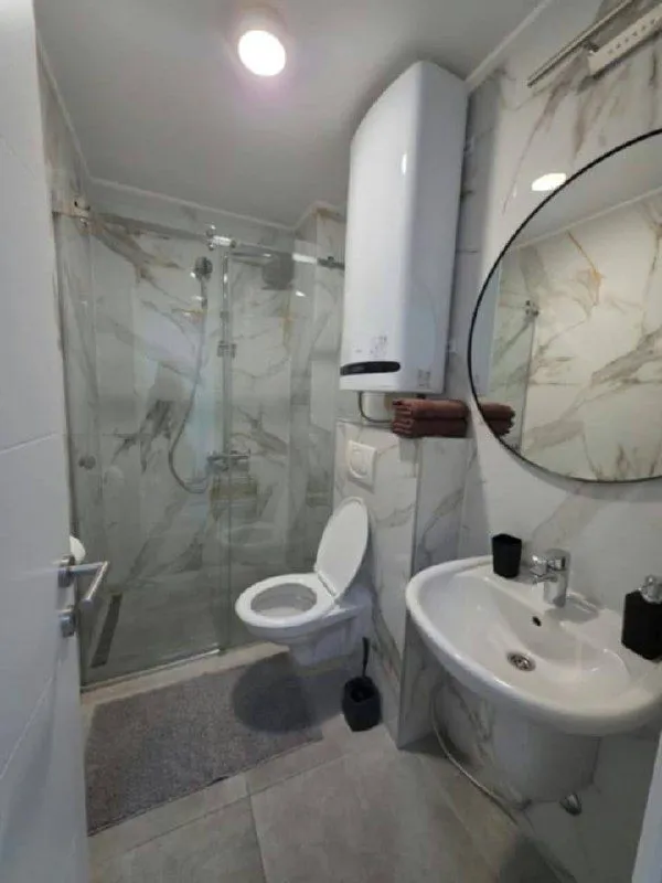 Modernly equipped bathroom with a shower cabin, sink, and toilet.