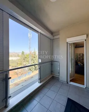 Natkriveni balkon sa staklenom ogradom i pogledom na okolinu. - image 11