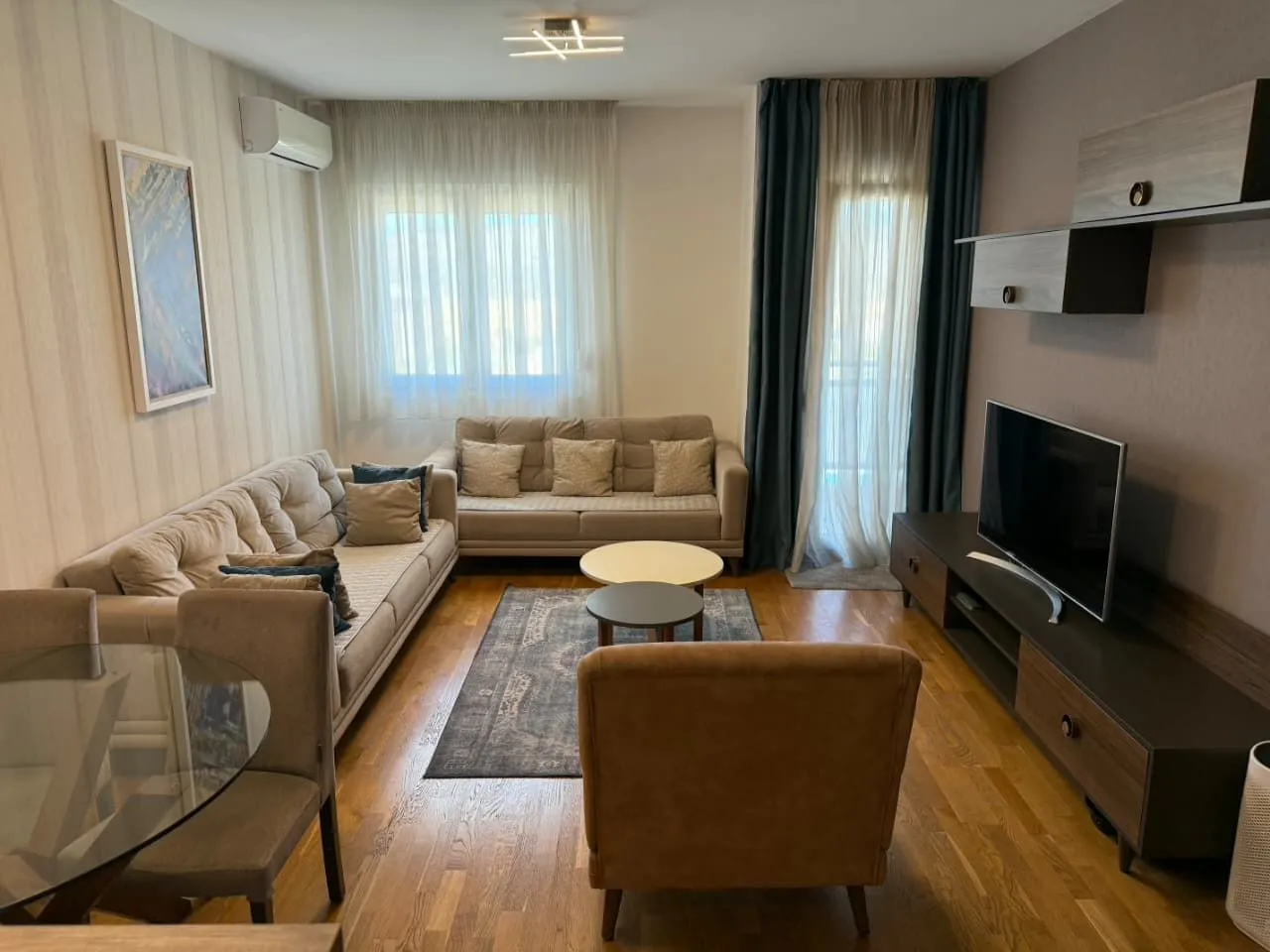 Namještena dnevna soba sa garniturom, televizorom i trpezarijskim stolom.