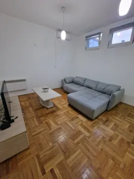 Dnevna soba sa ugaonom garniturom, stočićem i parketom na podu. - image 2