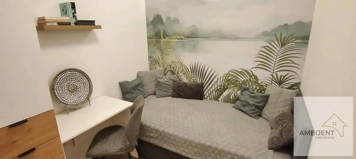Smaller bedroom with a bed, a desk, and decorative wall wallpaper.