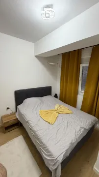 Spavaća soba sa bračnim krevetom, noćnim stočićem i žutim zavjesama. - image 4