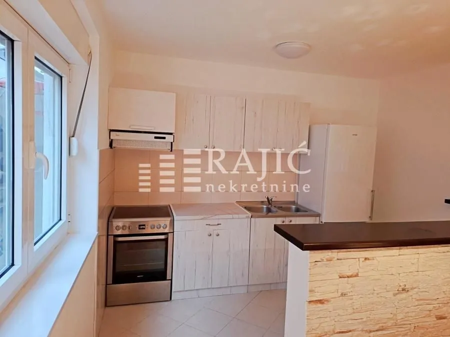 Small kitchen with wooden cabinets and white goods.