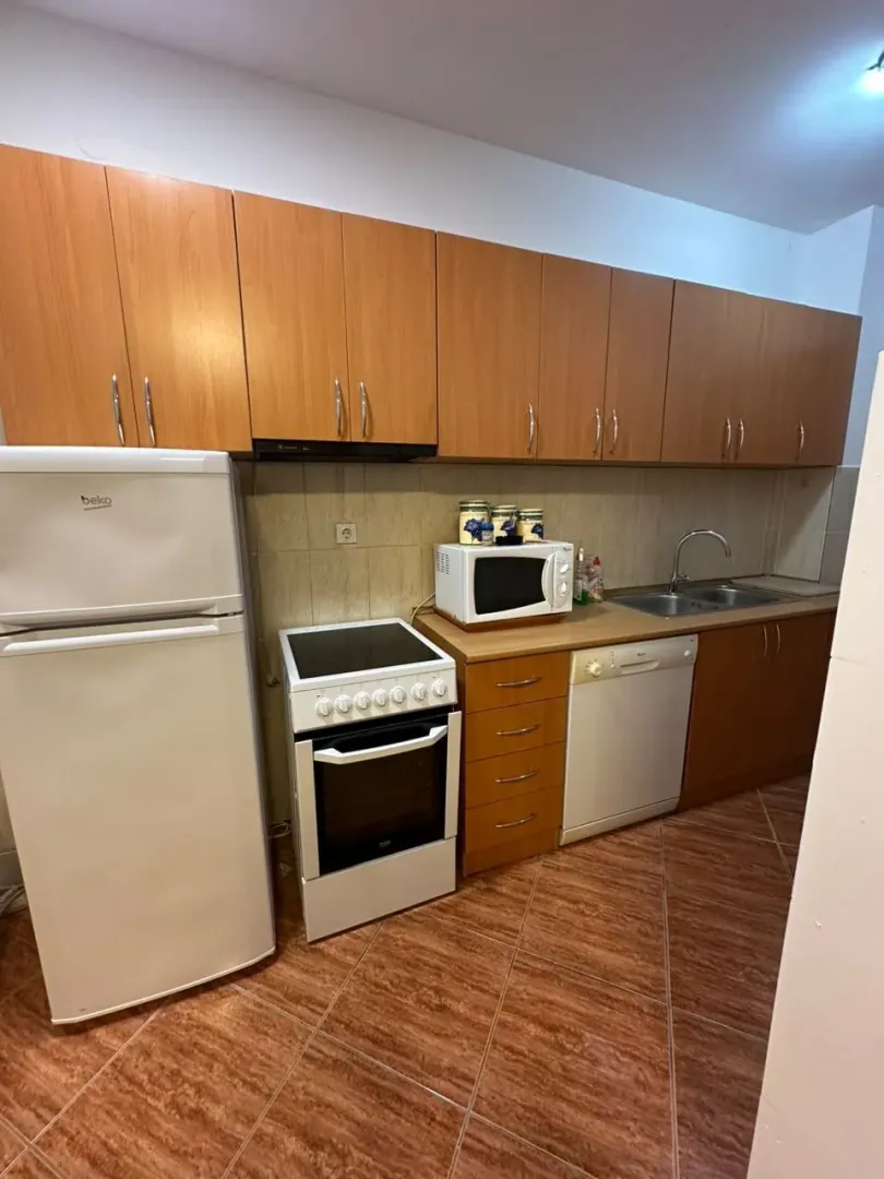 Small kitchen with wooden cabinets, refrigerator, stove, and sink.