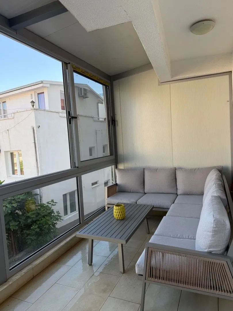 Zastakljena terasa sa garniturom za sedenje i stočićem.