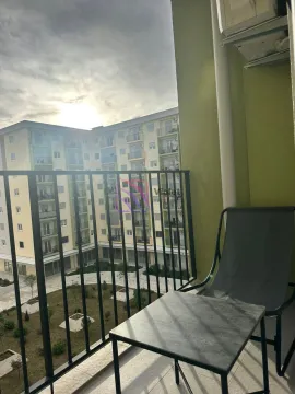Furnished balcony with a table and chair and a view of the building courtyard. - image 7