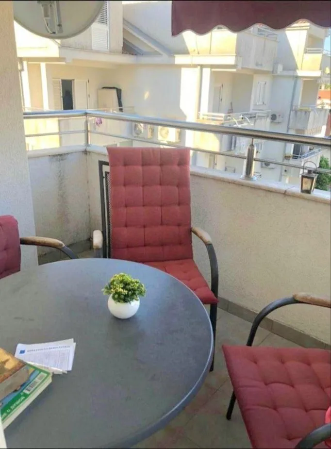 Namještena terasa sa stolom, stolicama i pogledom na okolne zgrade.