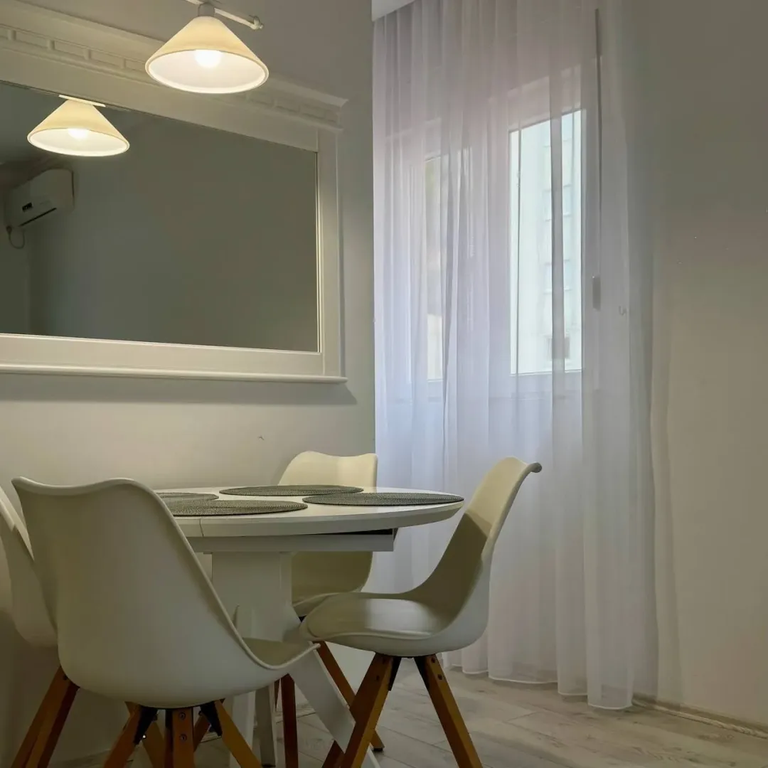 Dining area with a white table and modern chairs by the window.