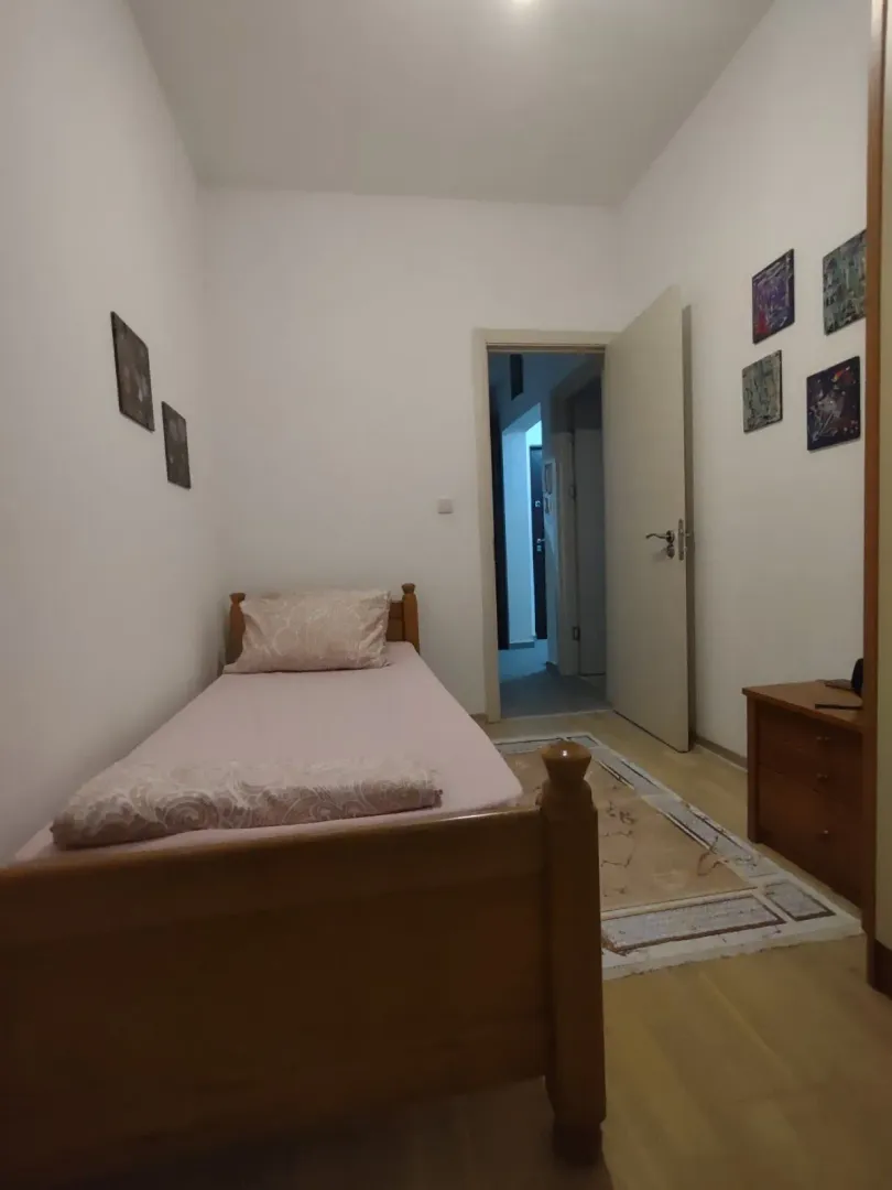 Manja spavaća soba sa drvenim krevetom i noćnim stočićem.