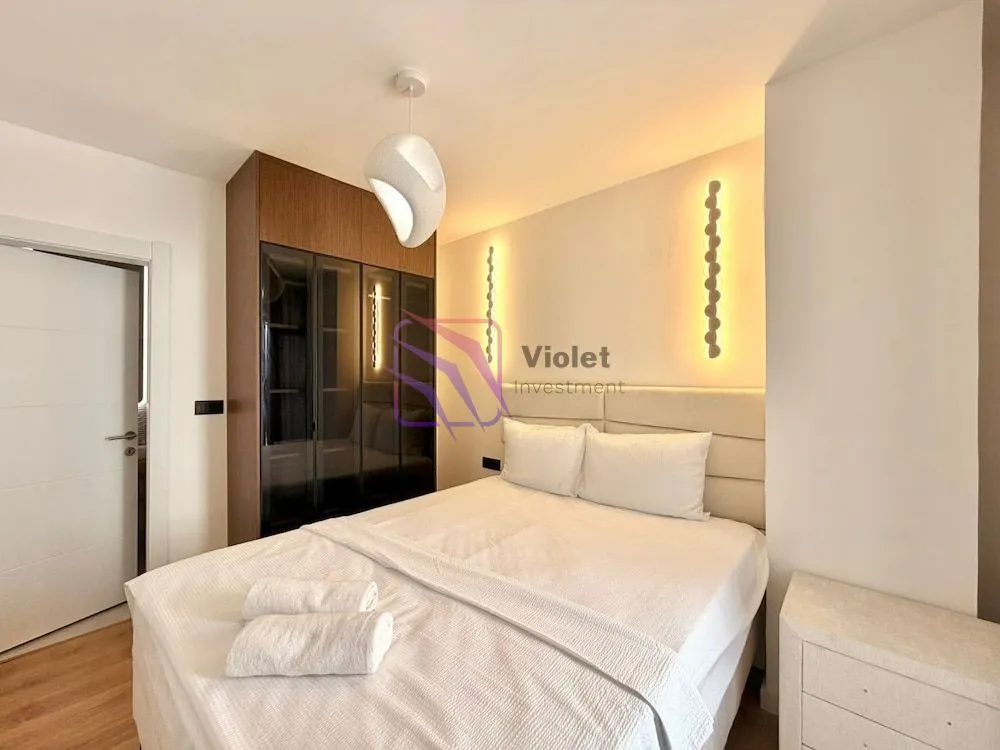 Modern bedroom with a double bed, built-in wardrobe, and decorative lighting.