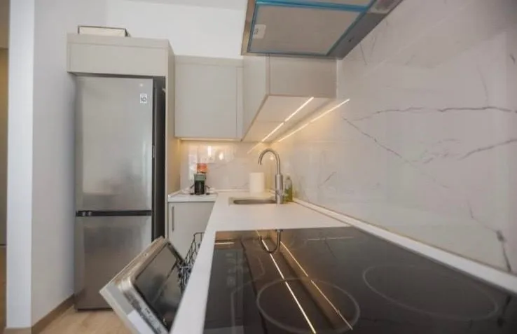 Modern and bright kitchen with a built-in cooktop and refrigerator.