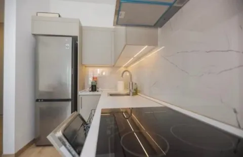Modern and bright kitchen with a built-in cooktop and refrigerator. - image 4