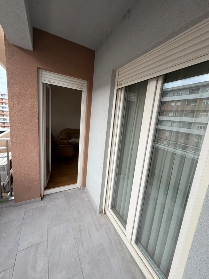 Manji popločani balkon sa balkonskim vratima i prozorom.