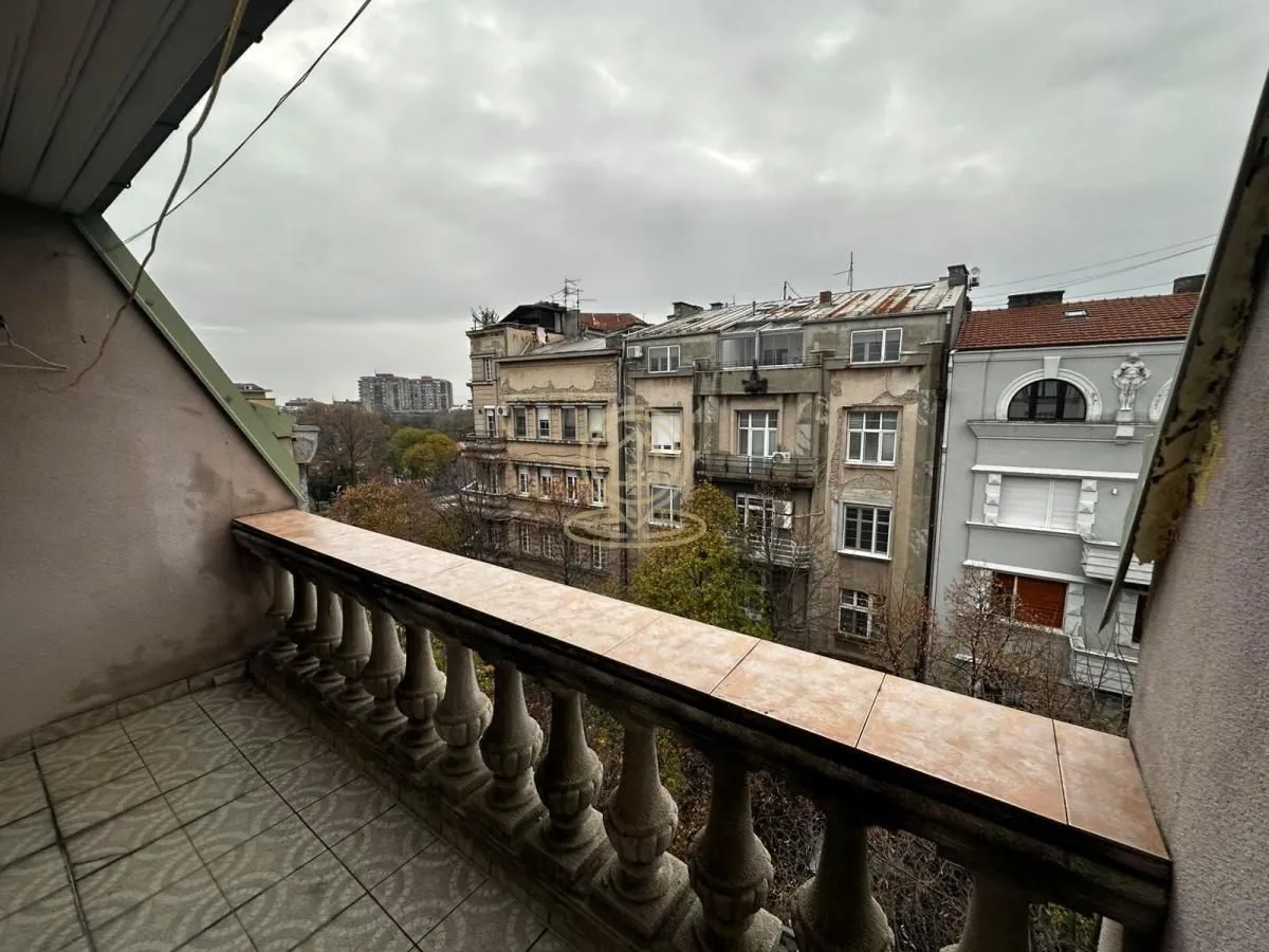 Balkon sa kamenom ogradom i pogledom na gradske zgrade.