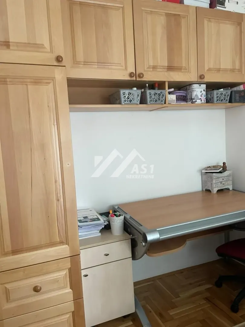 Radni sto sa drvenim elementima i visećim ormarićima u sobi.