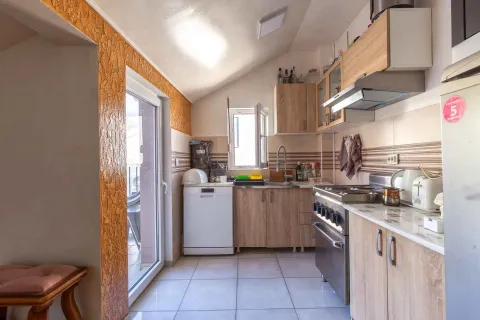 Svijetla kuhinja sa drvenim elementima i izlazom na balkon. - image 7