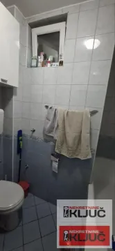 Pogled na dio kupatila sa WC šoljom, pločicama i prozorom. - image 9