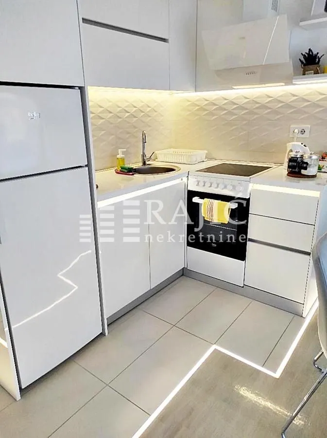 Modern white kitchen with built-in appliances and lighting.