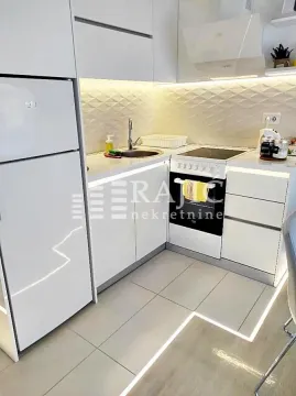Modern white kitchen with built-in appliances and lighting. - image 6