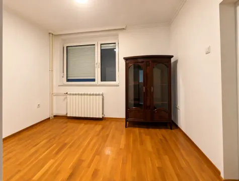 Prazna soba sa drvenim podom, prozorom i tamnim drvenim ormarom. - image 8