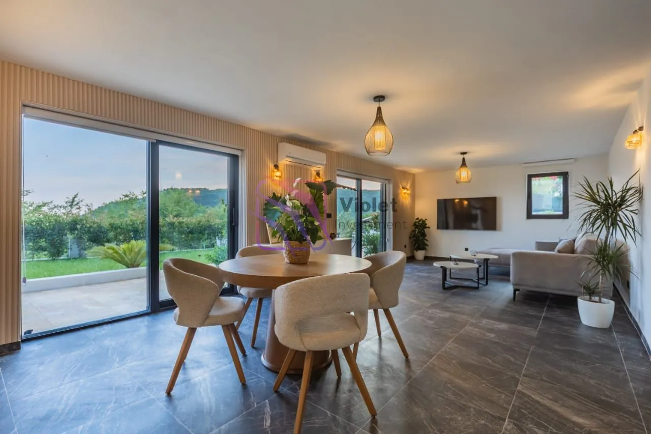 Spacious living room with a dining area and large glass surfaces.