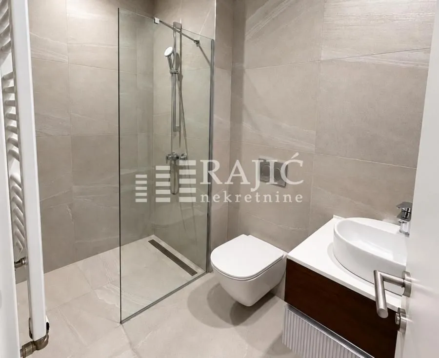 Modern bathroom with a walk-in shower, washbasin, and toilet.