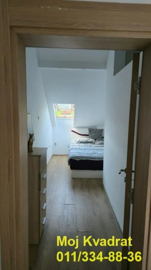 Pogled iz hodnika na spavaću sobu sa krevetom i krovnim prozorom.