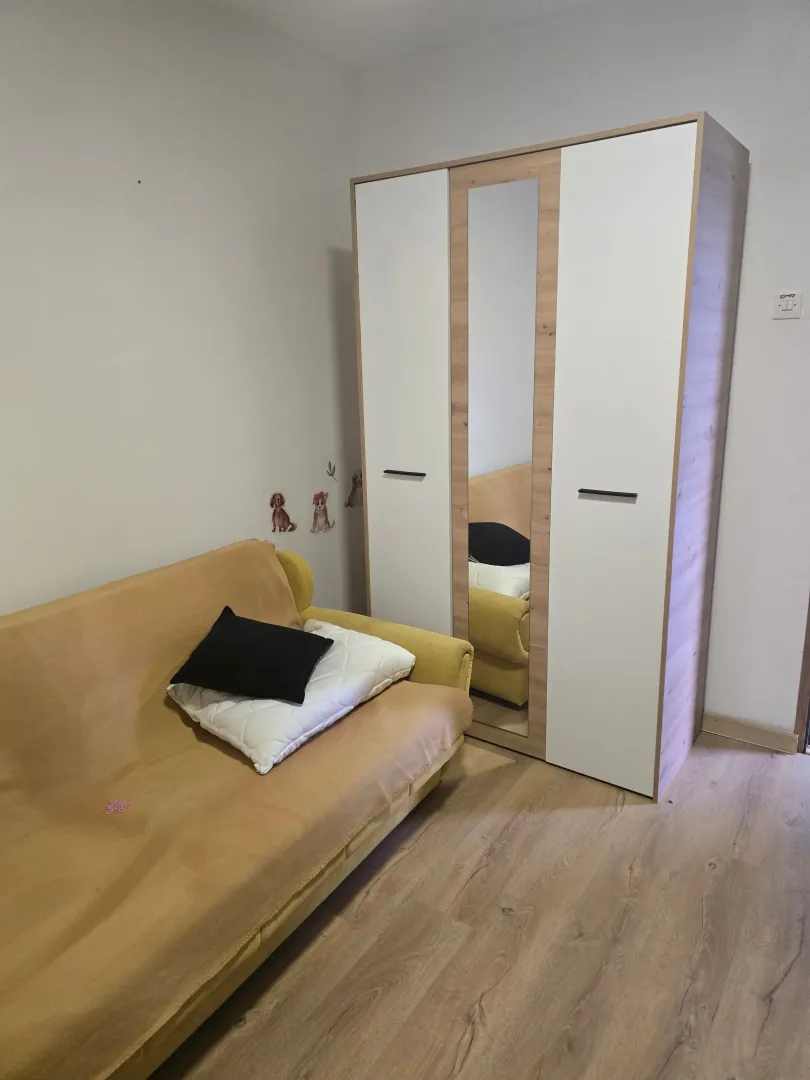 Nameštena spavaća soba sa kaučem i ormarom.