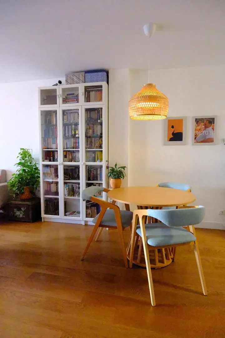 Dining table with chairs and a white bookcase in the living room.