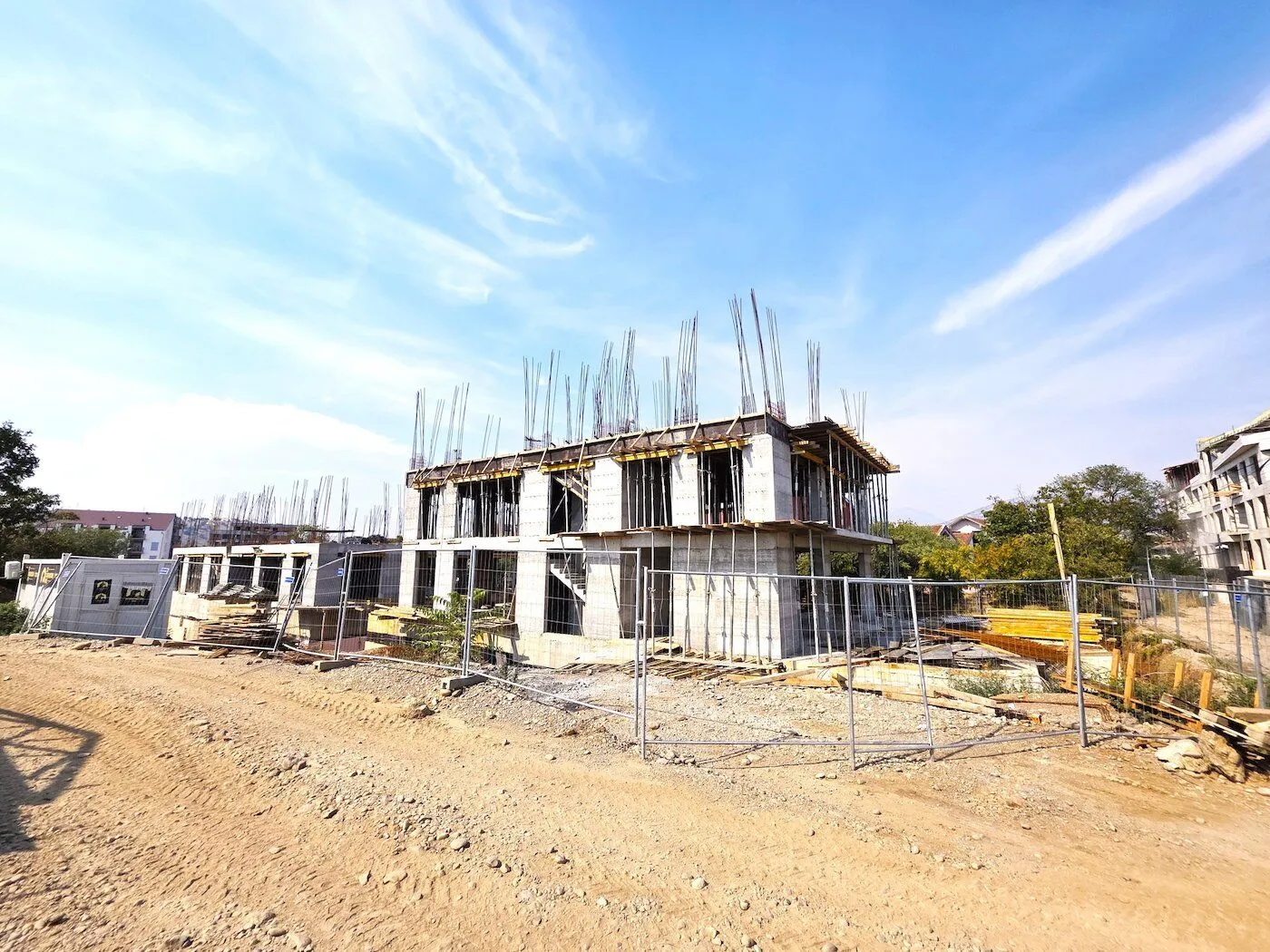 View of a residential building under construction with a construction site and protective fence.