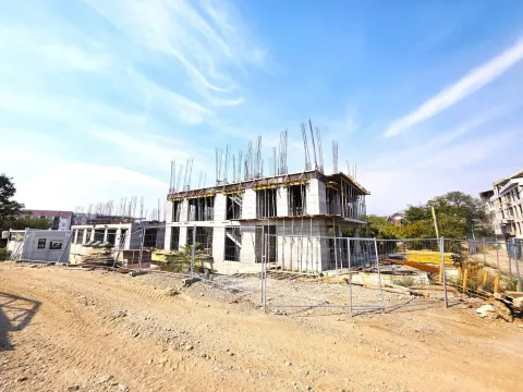 View of a residential building under construction with a construction site and protective fence. - image 8