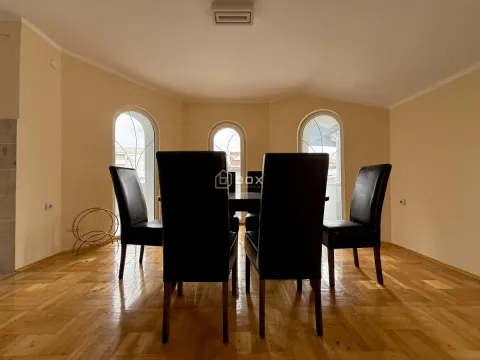 Dining area with a table and black chairs in front of arched windows. - image 6