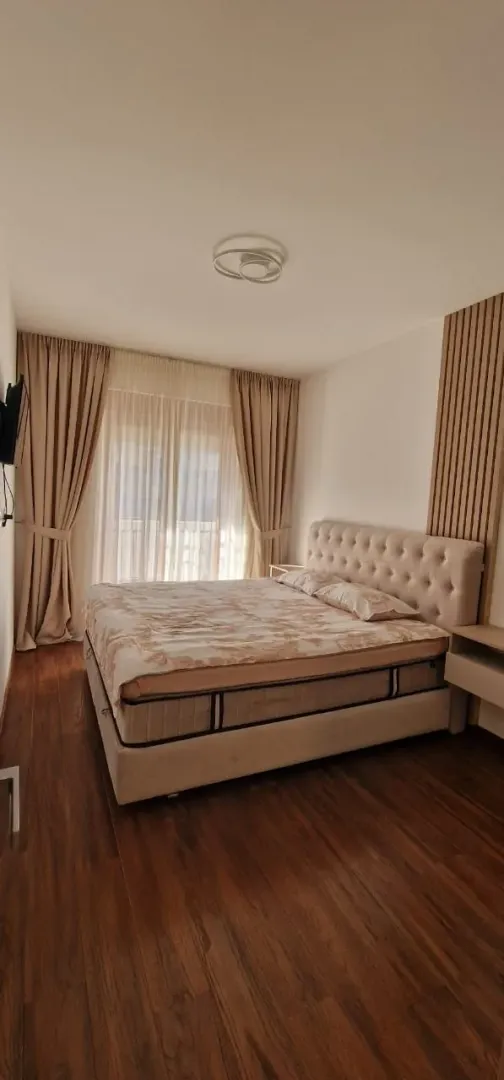 Svijetla spavaća soba sa velikim bračnim krevetom i bež zavjesama.