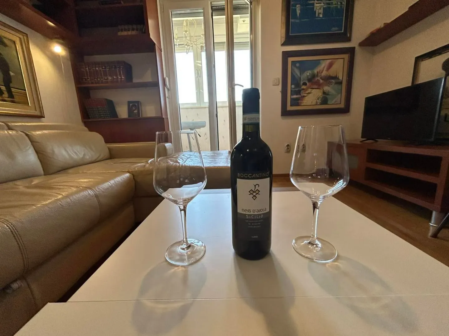 Living room with a sofa and a coffee table featuring a bottle of wine and glasses.